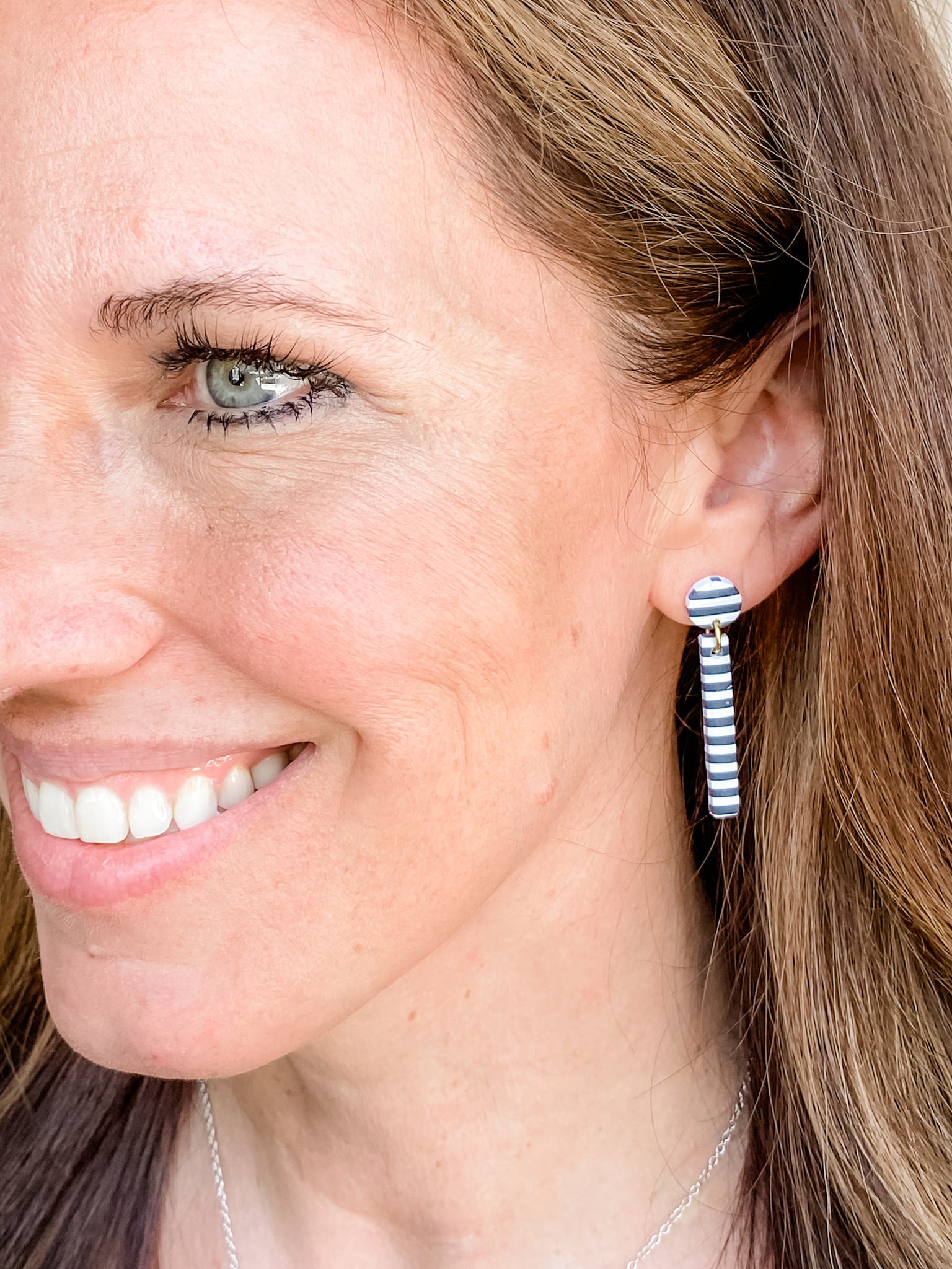 Woman wearing French or Paris striped dangle polymer clay earring black and white
